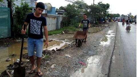 Sau cơn mưa đêm, người dân phải dùng xe rùa đổ đất lấp những cái ao mới xuất hiện trước cổng nhà. Hai thanh niên này đã đổ 7 xe đất nhưng chưa lấp xong.
